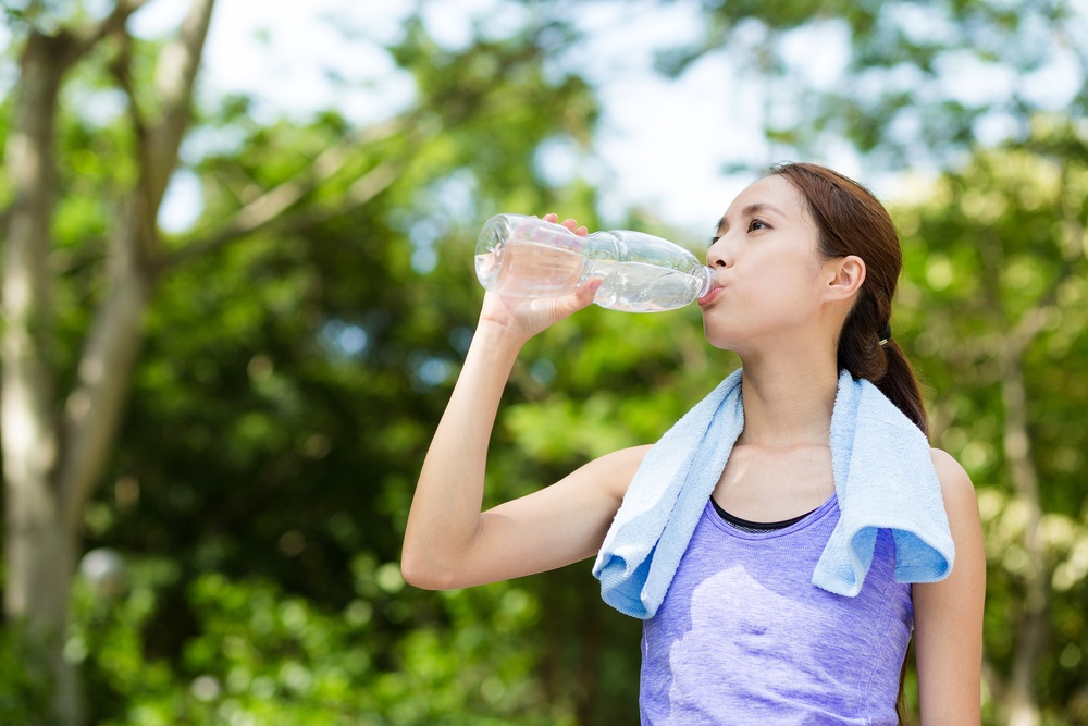 Athlete woman drinking water from a plastic bottle