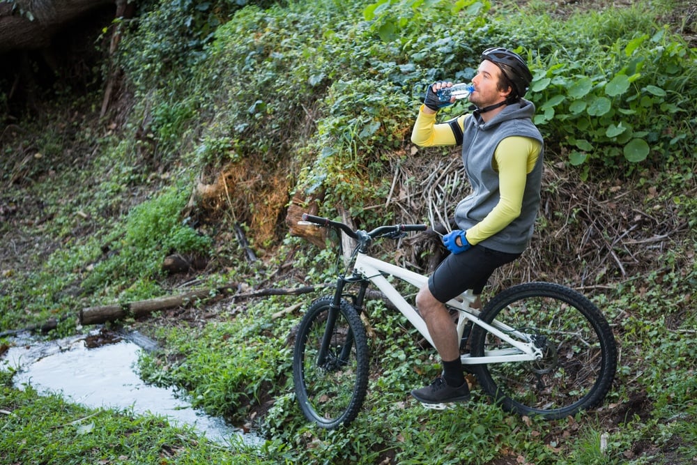 Male mountain biker drinking water in the forest